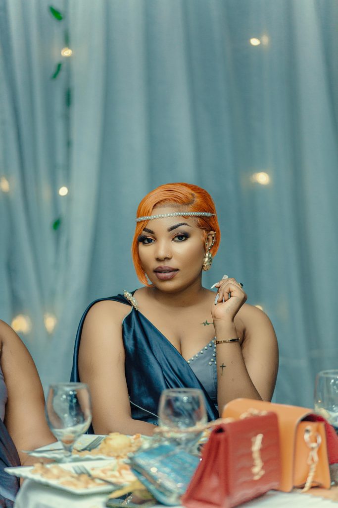 Stylish woman with orange hair and glamorous dress at a formal dinner setting.